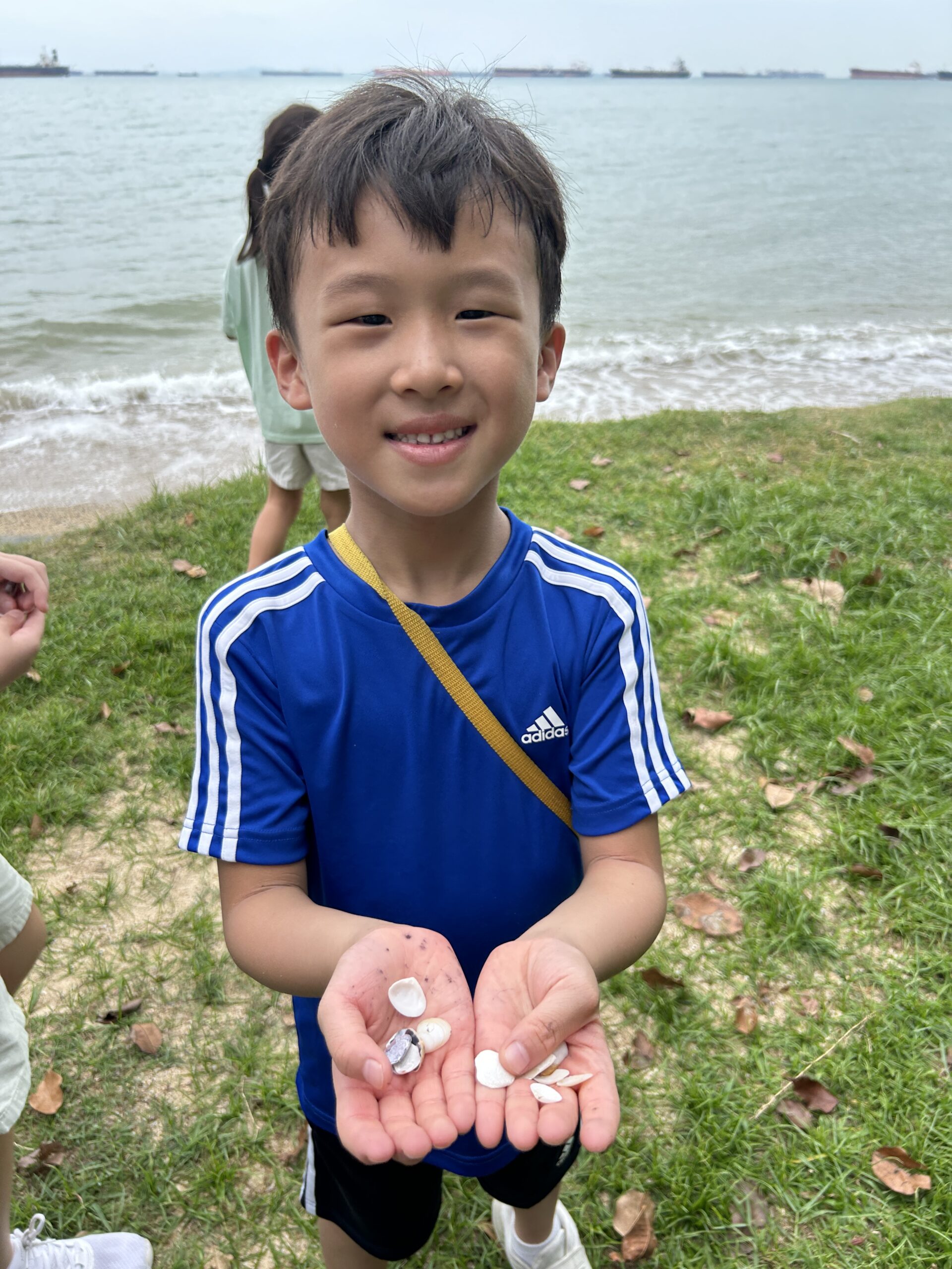 Four children walking barefoot by the sea at Singapore school holiday camp