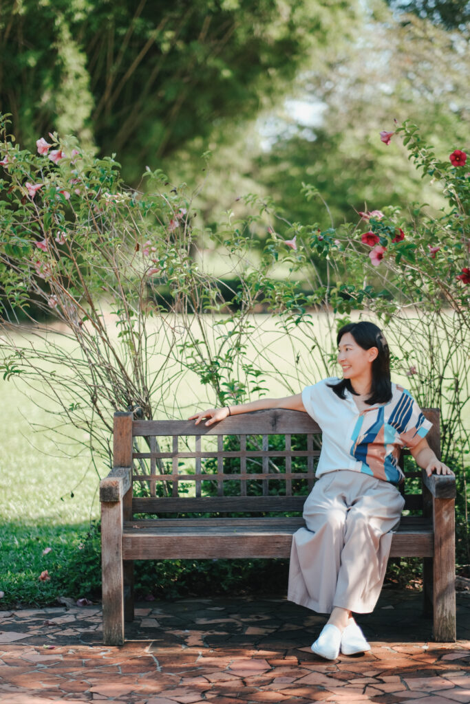 Vernessa Chuah, parenting coach in Singapore, sitting on a garden bench in a park